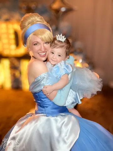 Cinderella in her ballgown holding a toddler in a matching light-blue tutu dress