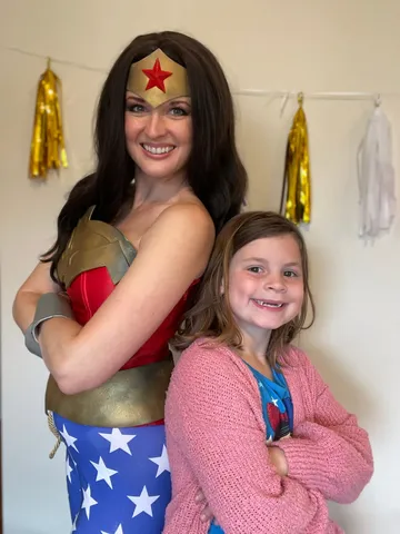 Wonder Woman posing with a young girl who has her arms crossed like a superhero