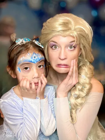 Elsa and a girl with snowflake face paint pulling matching wide-eyed faces
