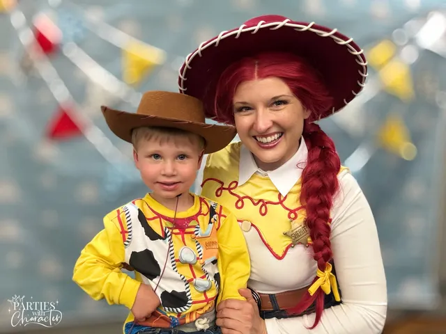 Jessie and a young boy in a brown cowboy hat and Woody costume, both smiling at the camera