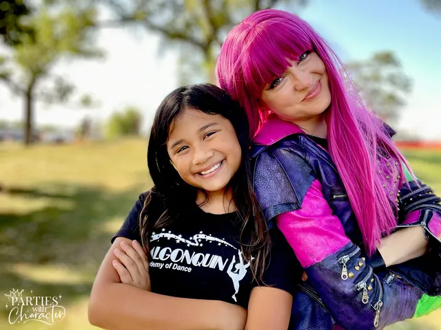 Mal hugging a girl in a black tee at an outdoor fall festival