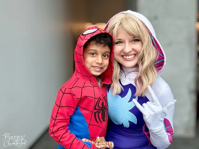 Ghost Spider fist-bumping a boy dressed as Spider-Man in a lobby