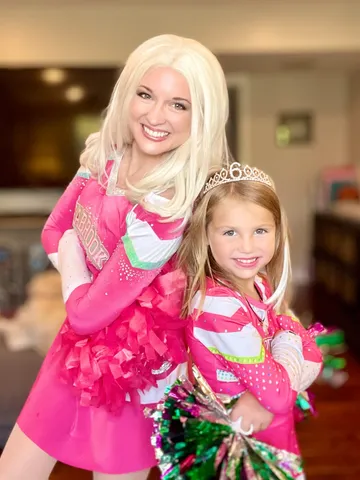 Addison hugging a young girl in a pink dress and tiara
