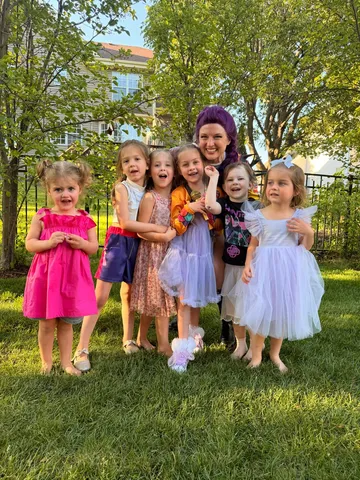 Rumi posing with a group of young girls at an outdoor party