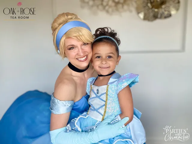 Cinderella cheek-to-cheek with a young girl wearing a matching pale-blue gown