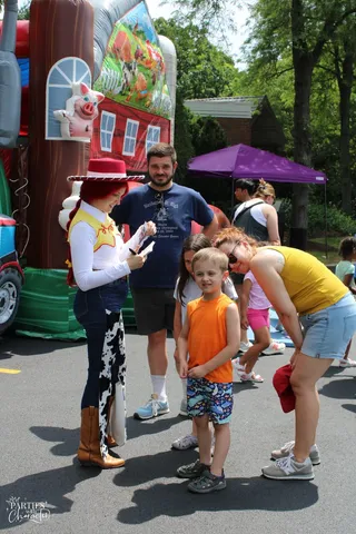 Jessie meeting a group of children beside a bounce house at an outdoor summer event