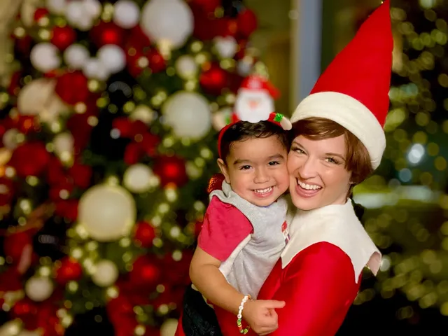 Elf on the Shelf laughing with a young boy pointing at a decorated Christmas tree