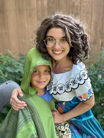 Mirabel hugging a young boy in a green hoodie outdoors