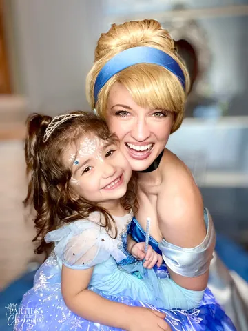 Cinderella hugging a young girl wearing a tiara and snowflake face paint