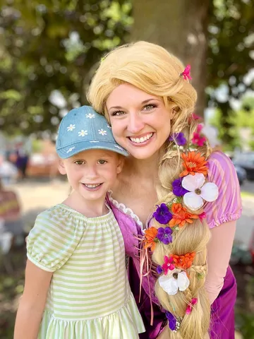 Rapunzel with a young girl in a ball cap at a park