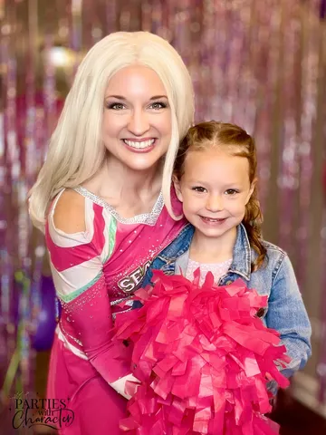 Addison posing with a girl in a denim jacket holding a pom-pom