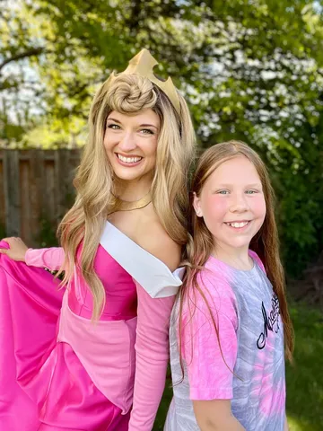 Aurora with a young girl in a tie-dye shirt in a backyard