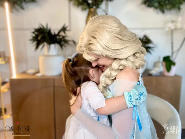 A young girl hugging Elsa tightly at a tea room party table