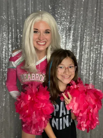 Addison posing with a preteen girl wearing glasses and a pom-pom