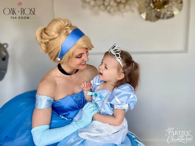 Cinderella smiling at a toddler in a sparkly tiara held close beside her