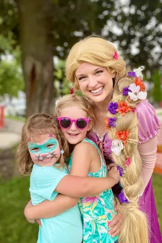 Rapunzel with two giggling girls making silly faces at a park