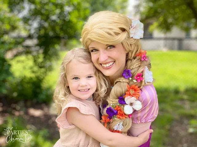 Rapunzel hugging a toddler in a pink dress outdoors