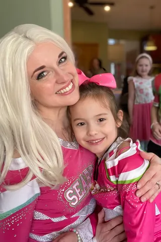 Addison hugging a young girl wearing a pink bow at a party