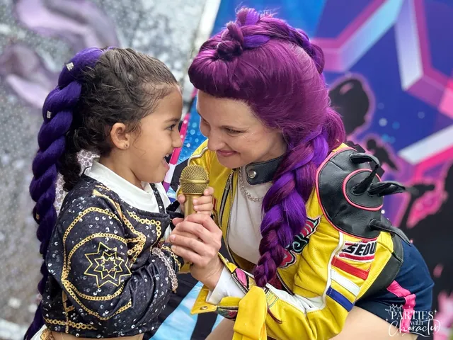 Rumi singing into a gold microphone face to face with a young girl wearing purple braids
