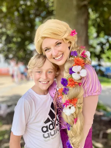 Rapunzel with a young boy in an Adidas shirt among the trees