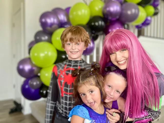 Mal posing with three children, one in a spider-themed superhero costume