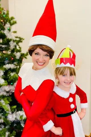 Elf on the Shelf and a young girl both wearing pointed elf hats