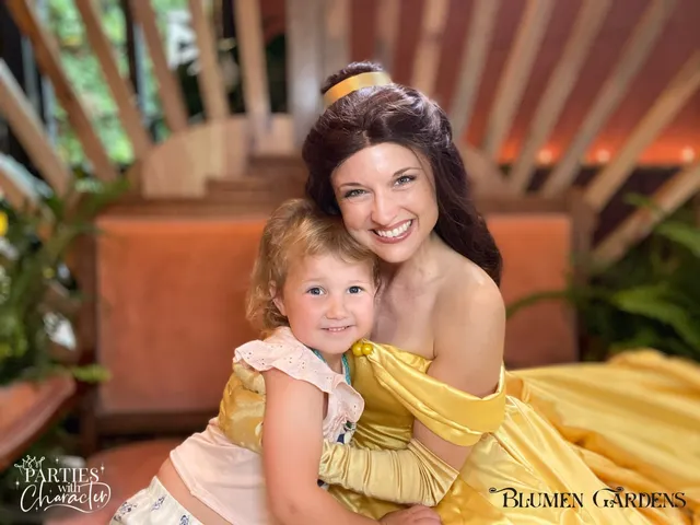 Belle sitting with a toddler girl in a yellow dress on a garden bench