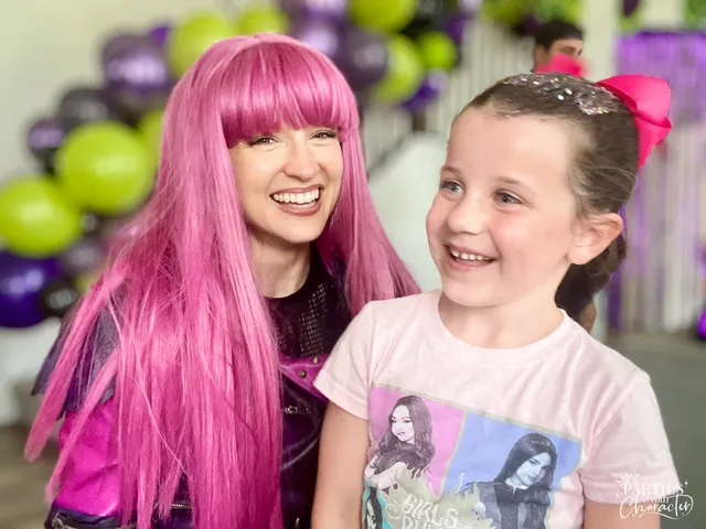 Mal laughing with a young girl wearing a Descendants t-shirt at her party