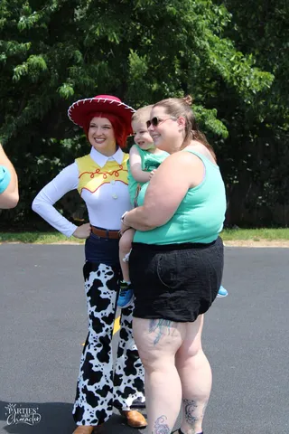 Jessie posing with a parent and toddler outdoors at a community event