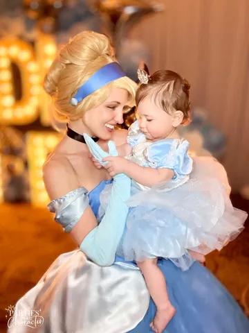Cinderella holding a baby in front of glowing marquee letters at the venue