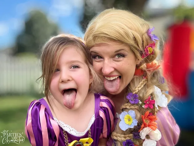 Rapunzel and a young girl sticking their tongues out together at an outdoor party