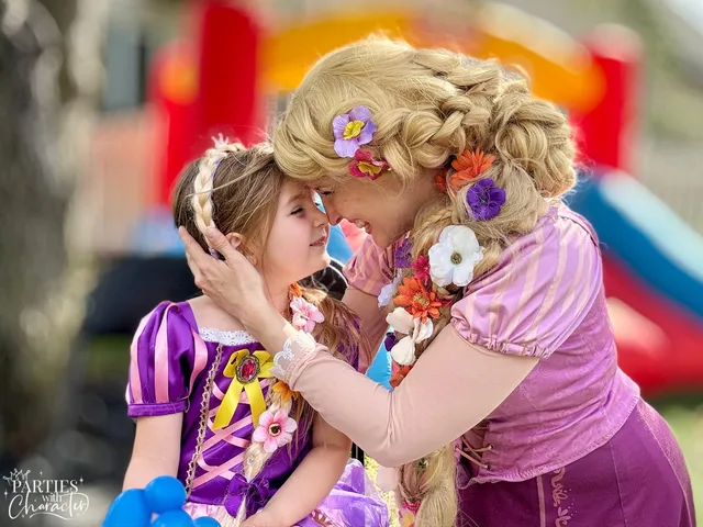 Rapunzel forehead to forehead with a young girl in front of a bounce house