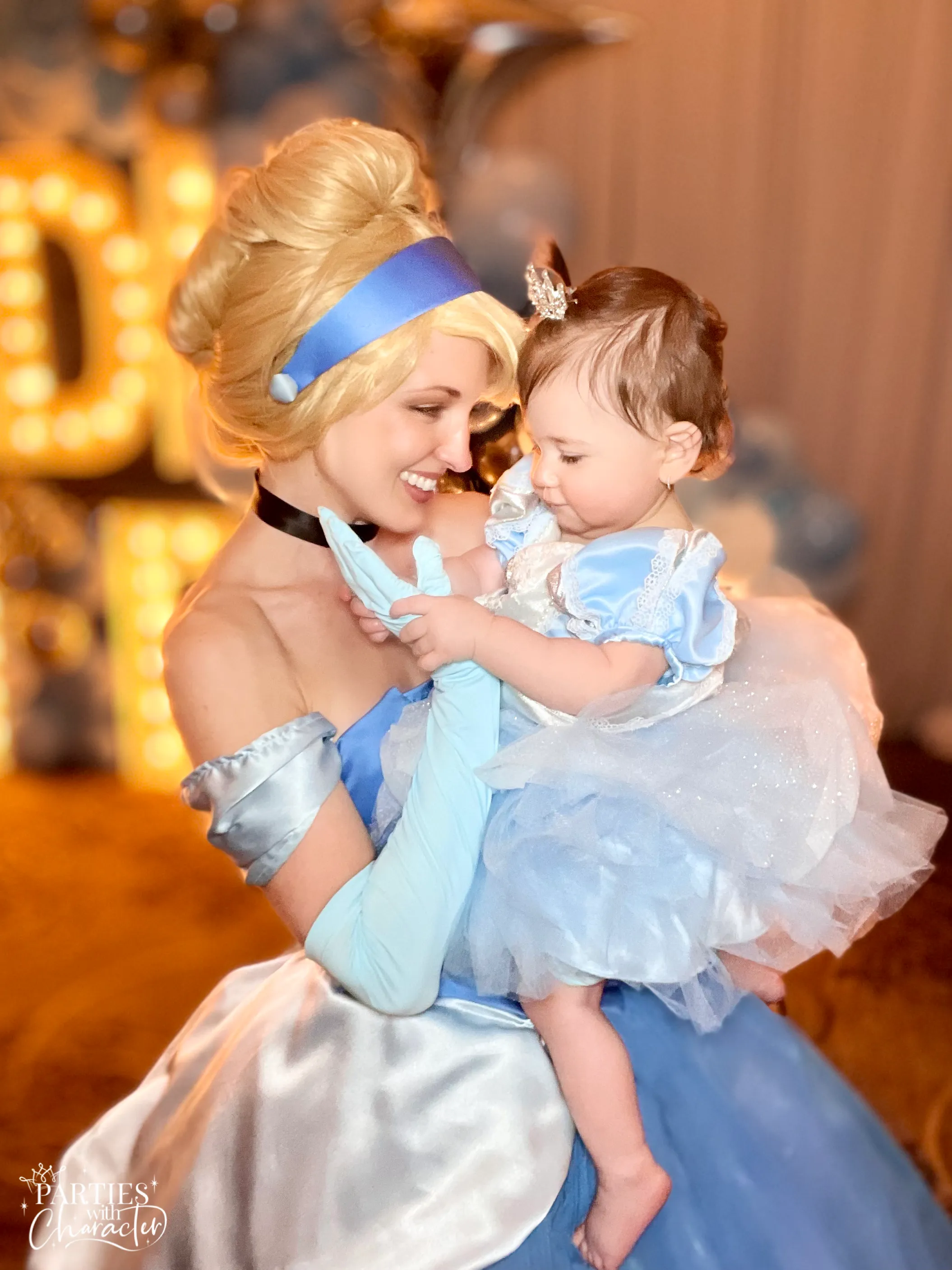 Jessica as Cinderella holding a child dressed in a matching costume at a birthday party