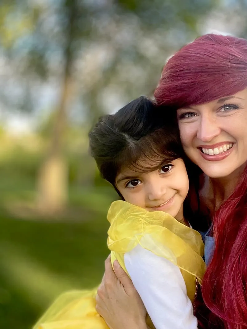 Ariel and a young girl smiling cheek to cheek outdoors