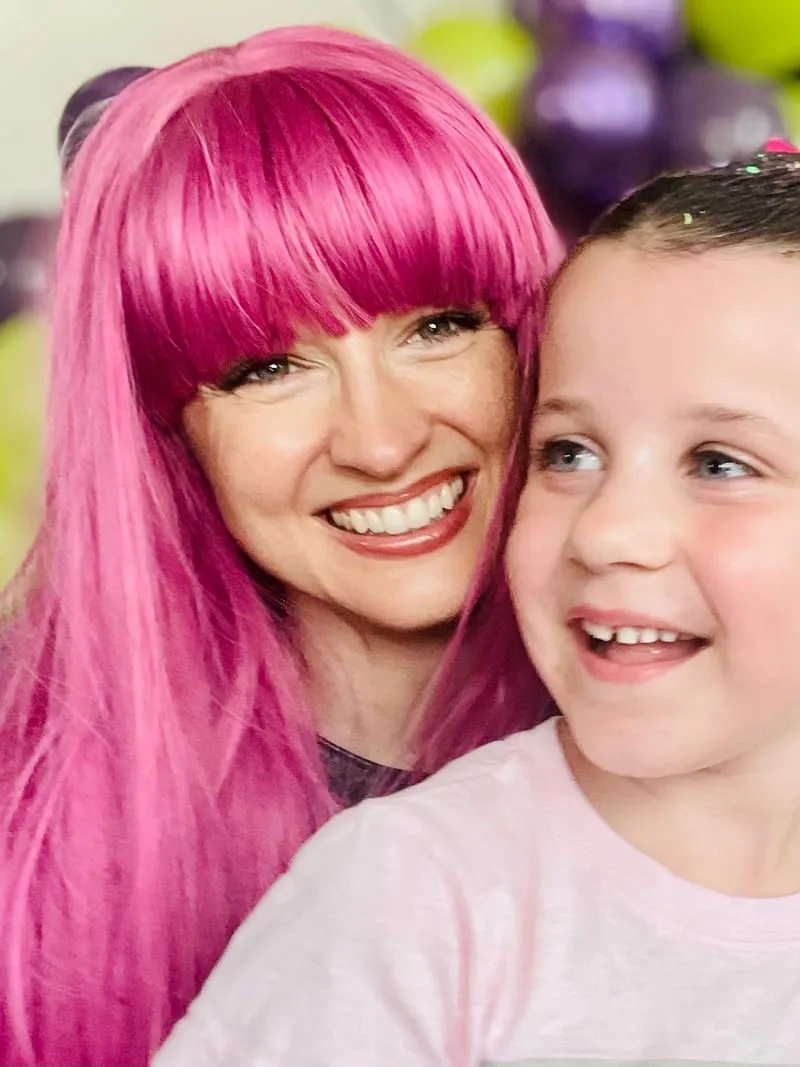 Mal laughing cheek to cheek with a young girl wearing a sparkly hair bow