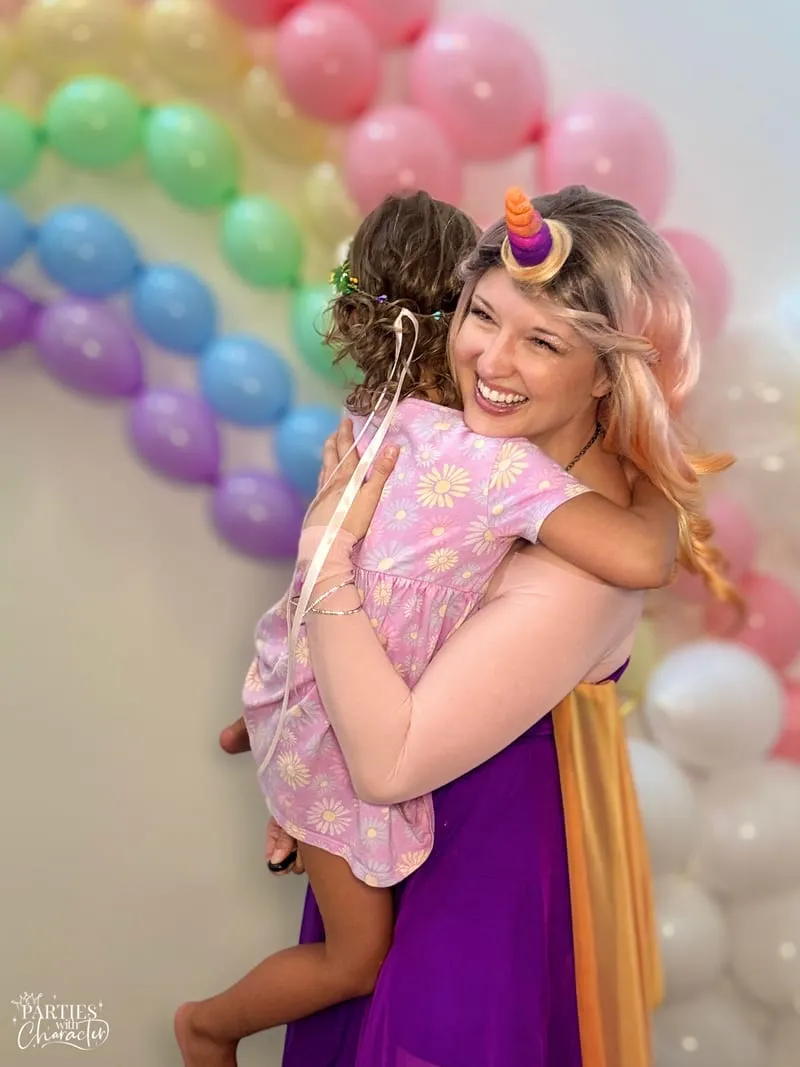 Unicorn Princess carrying a smiling young girl in a pink dress